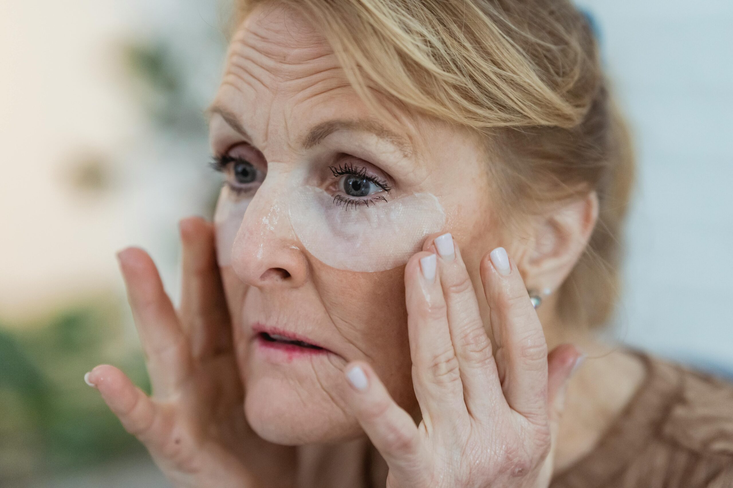 Elderly woman applying collagen eye patches